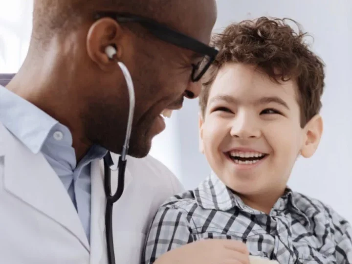 A smiling boy getting a check up by a doctor